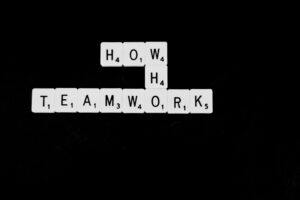 scrabble tiles spelling, 'how, who, teamwork'